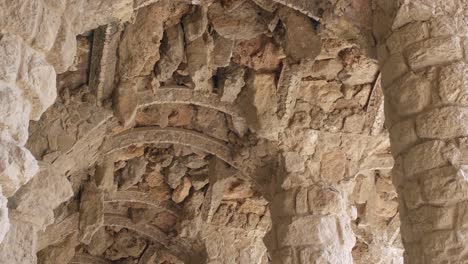 Sendero-Con-Columnas-Bajo-El-Viaducto-De-La-Calzada-Con-Techo-De-Bóveda-De-Piedra-En-El-Parque-Guell-En-Barcelona,-Cataluña,-España