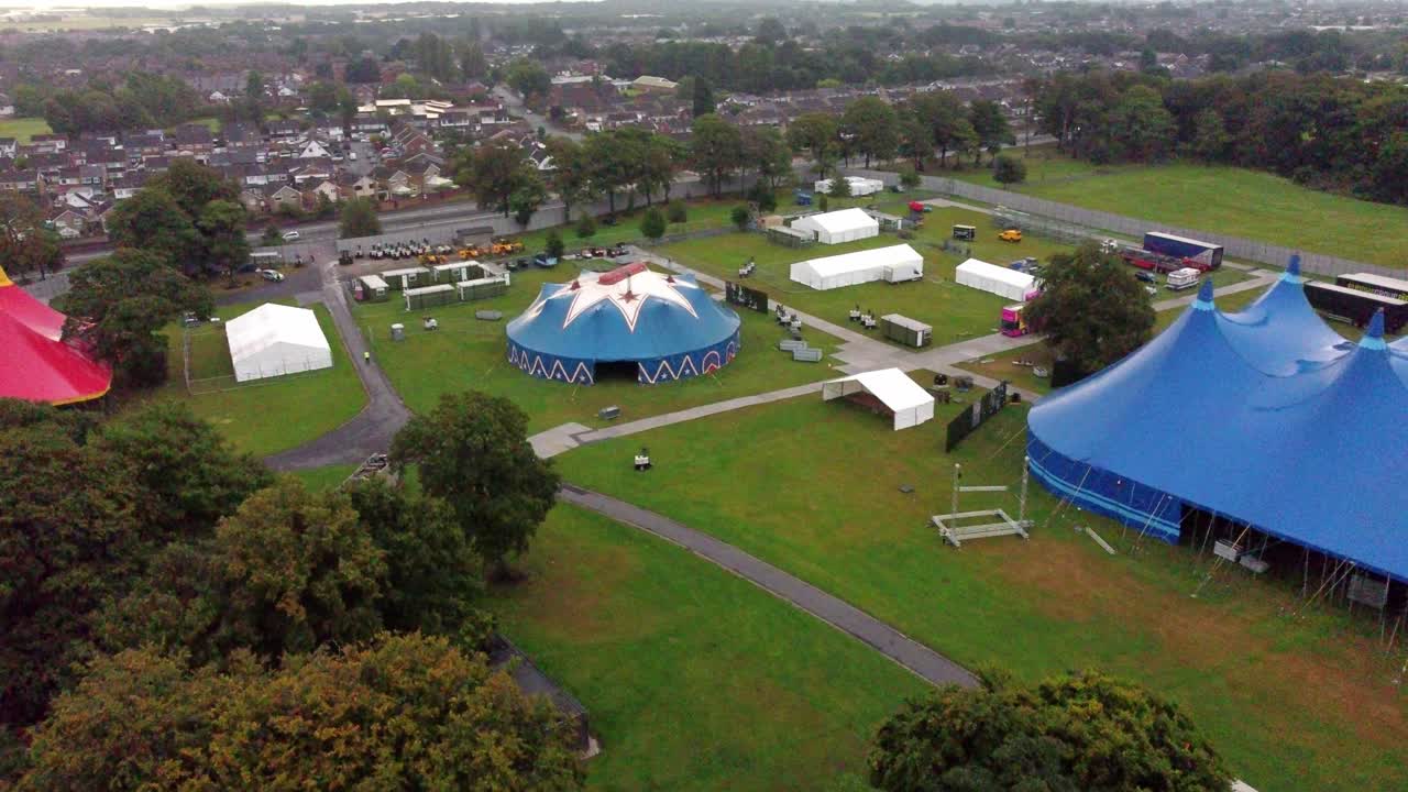 toma de exploración aérea lenta que se dirige hacia una carpa azul redonda donde actuarán los artistas
