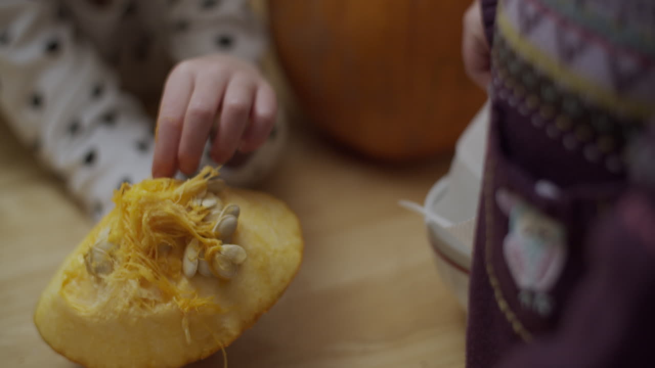 dos niños pequeños quitando las semillas de una calabaza para halloween