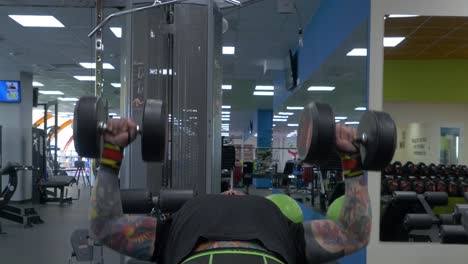 man performing dumbbell chest press in gym