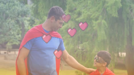 animation of hearts over caucasian father and son in superhero costumes