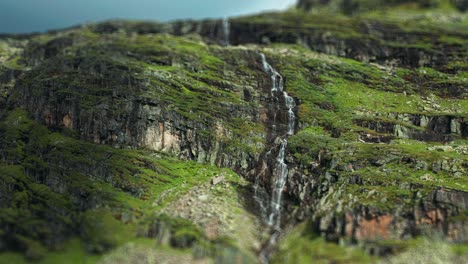 a waterfall in the lush green mountainous valley