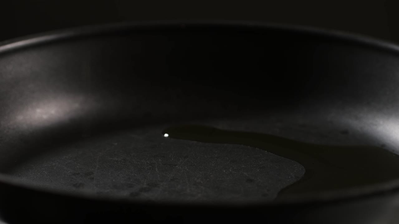 Adding an oil on black pan close-up. Chef going to cook food on a boiling pan for frying some dishes High quality 4k footage