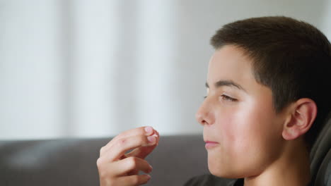 side view of young boy eating cake, enjoying the treat with light reflecting off his face, he looks relaxed and satisfied, savoring the moment with a joyful expression