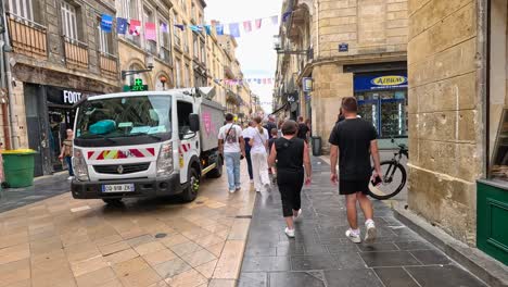 couple walks down street, passing garbage truck