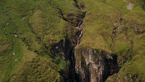 una espectacular toma aérea de una cascada en la ladera de una montaña, en las tierras altas de escocia | el valle perdido, glencoe, escocia | filmado en 4k a 30 fps