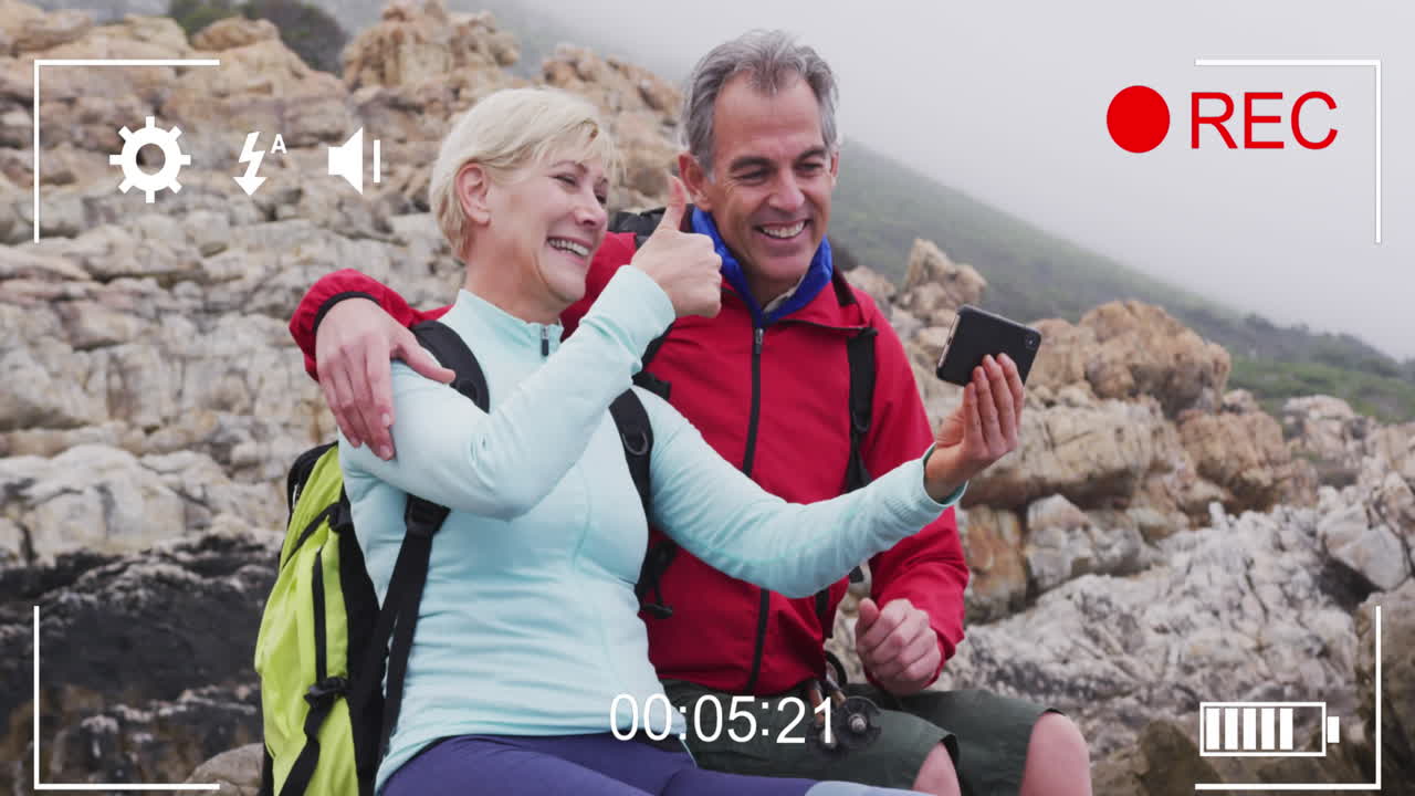 해변에서 셀카를 촬영하는 행복한 백인 노인 부부 위의 스마트폰 비디오 인터페이스 화면