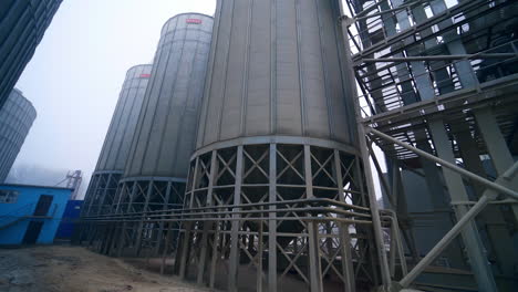 huge steel tanks of grain silos standing on the massive metal supports. moving closer to the basis of granary cisterns at the modern factory.