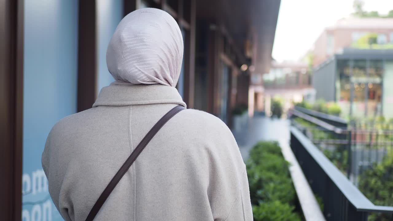 A woman wearing a hijab walking down a city street