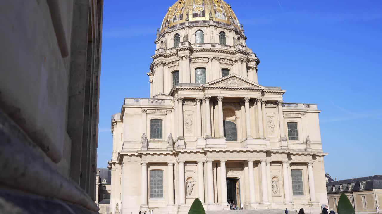 Historic monument Les Invalides under a sunny blue sky in Paris, with tourists exploring, in slow motion, stone wall