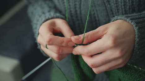 the hands of an unrecognizable woman knitting with green wool 3