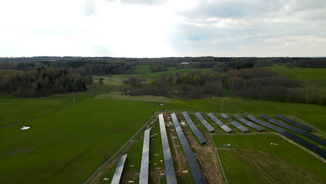 Aerial-flying-over-small-solar-power-plant-farm-in-green-field-of-Pieszkowo-Poland