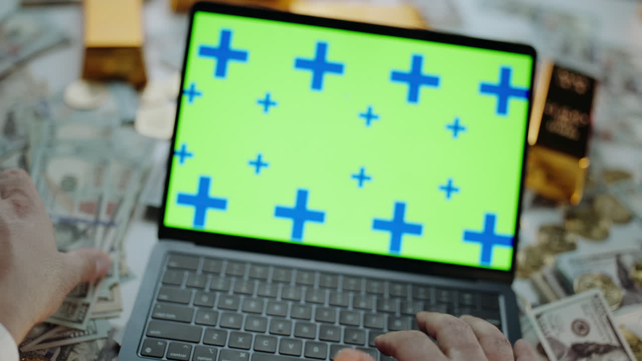 Laptop surrounded by money and gold bars