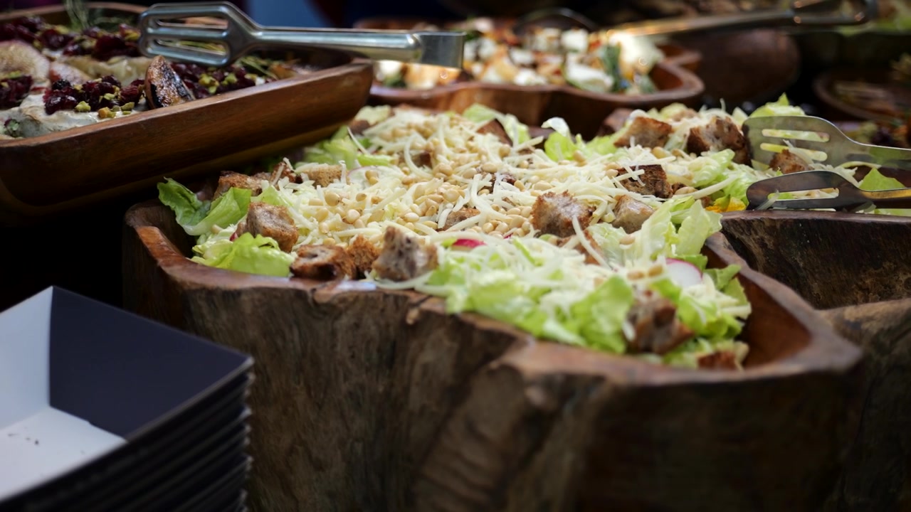 Primo piano di insalata fresca servita su un tavolo da buffet con lattuga, crostini e formaggio grattugiato, catering, ospitalità, alimentazione sana, ristorazione e banchetti per eventi