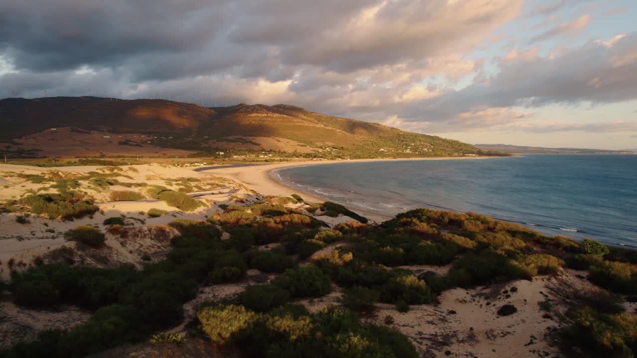 Ripresa da drone a bassa quota che sorvola la costa di Tarifa al tramonto