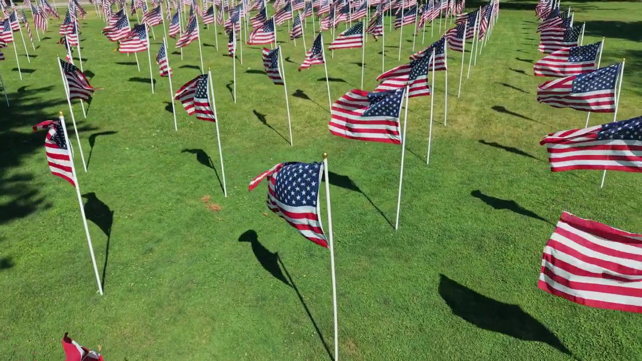 Close drone perspective of a Memorial Day garden with American flags fluttering for Independence Day and patriotic events, North Andover, Massachusetts, US