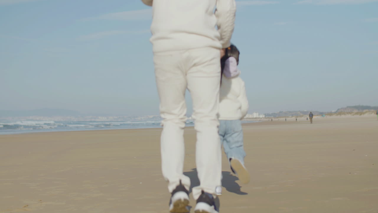 행복한 일본 아버지와 어린 딸이 해변에서 뛰고 있다