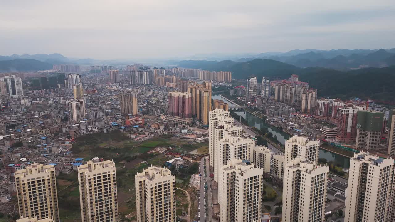 Aerial of Huishui in Guizhou, showcasing dense high-rise apartments, expanding urban districts and distant mountains, capturing the scale, growth and modern transformation of this Chinese cityscape