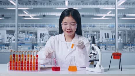 científica asiática haciendo experimentos con tubos de ensayo y escribiendo en un cuaderno en el microscopio de laboratorio. realizando experimentos, trabajando en el laboratorio analizando y encontrando muestras de tubo de ensayo
