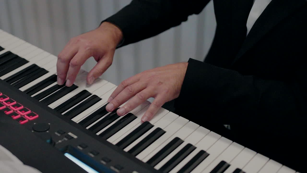 primer plano de las manos de un músico tocando un teclado de piano digital en un entorno formal