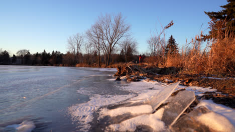 pan shot of a frozen lake in winter by sunset