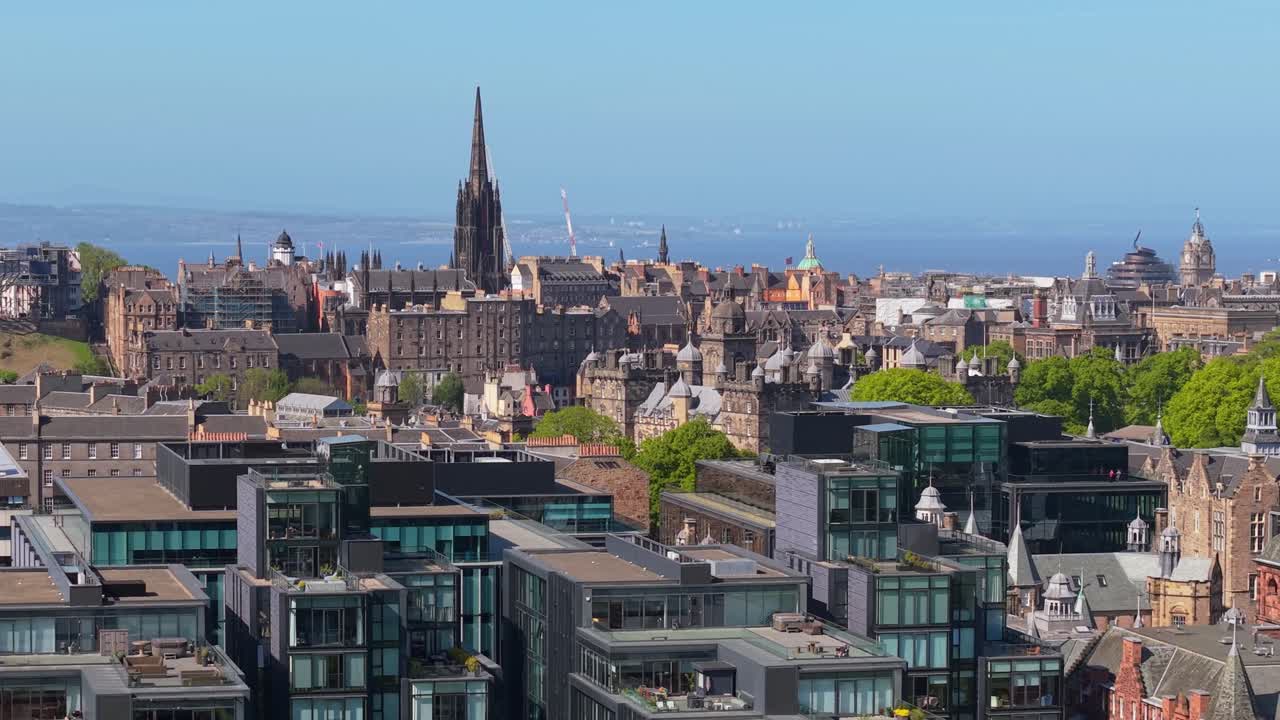 Drone flies parallel above Edinburgh, capturing The Hub and surrounding historic buildings, revealing the city’s gothic charm and architectural elegance