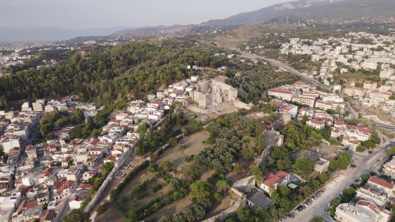 amplia toma circular del castillo de patras en la cima de una colina boscosa, paisaje urbano de patras que se extiende en la distancia