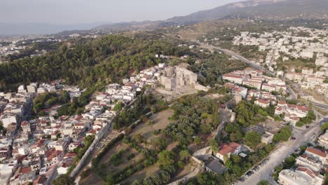 wide circling shot of patras castle on a forested hilltop, cityscape of patras sprawling in the distance