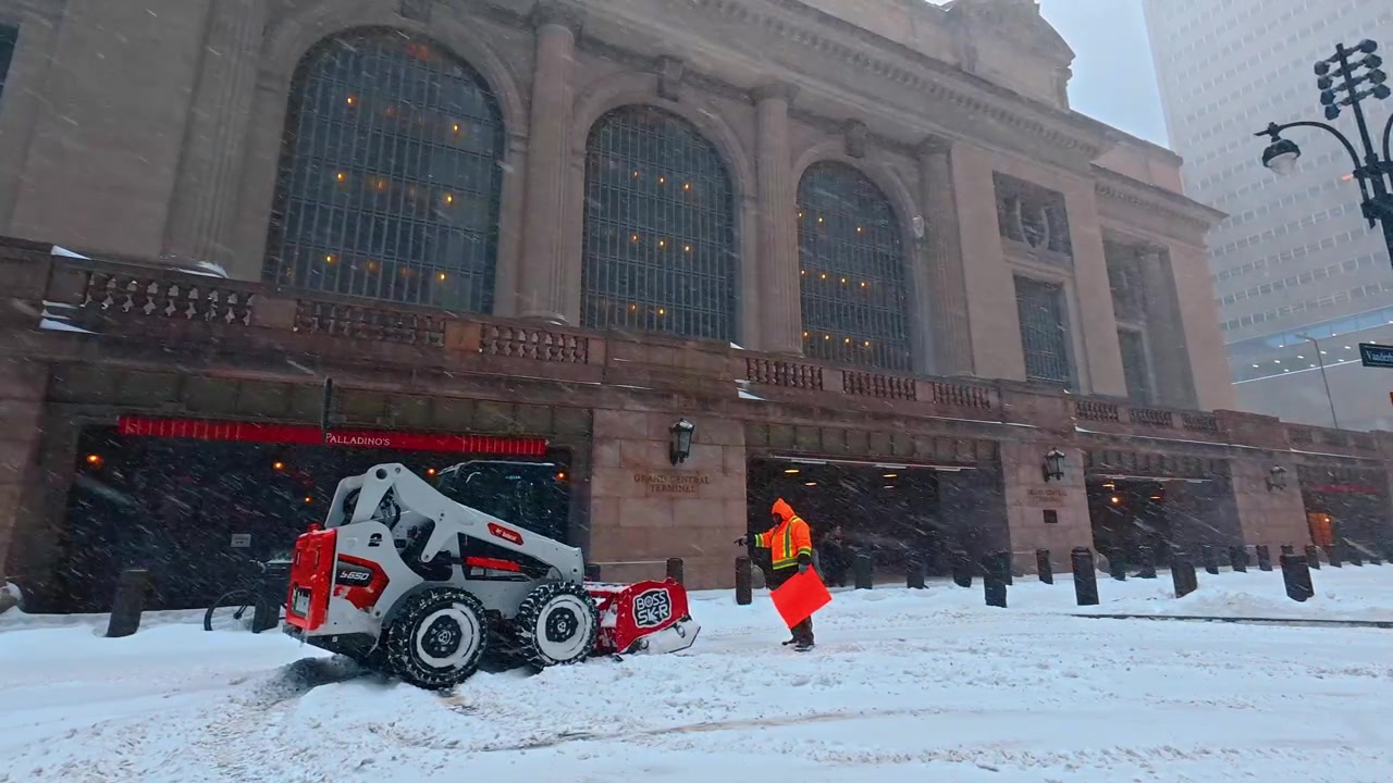 New York, USA, 25. december 2025: Gadescene med sneplov ved Grand Central Terminal. Udsigt fra gadeplan over snerydningsarbejde, buede vinduer og en fodgænger.