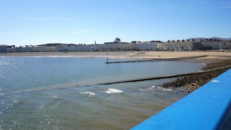 Llandudno-holiday-resort-town-hotels-along-promenade-seaside-seafront-as-blue-ocean-waves-wash-ashore