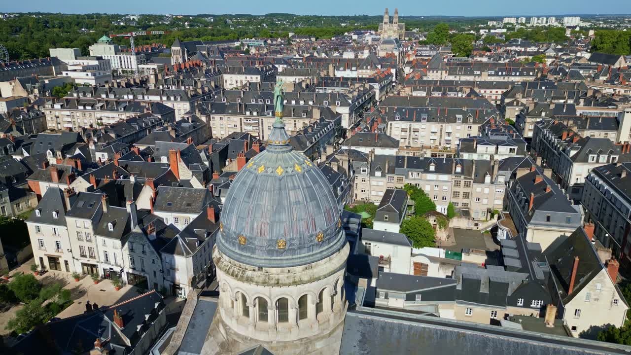 Tilt-down aerial overview of Basilique St Martin in Tours, France with clear blue sky and nearby buildings