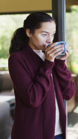 video vertical de una mujer biracial pensativa con vitiligo disfrutando de una taza de café