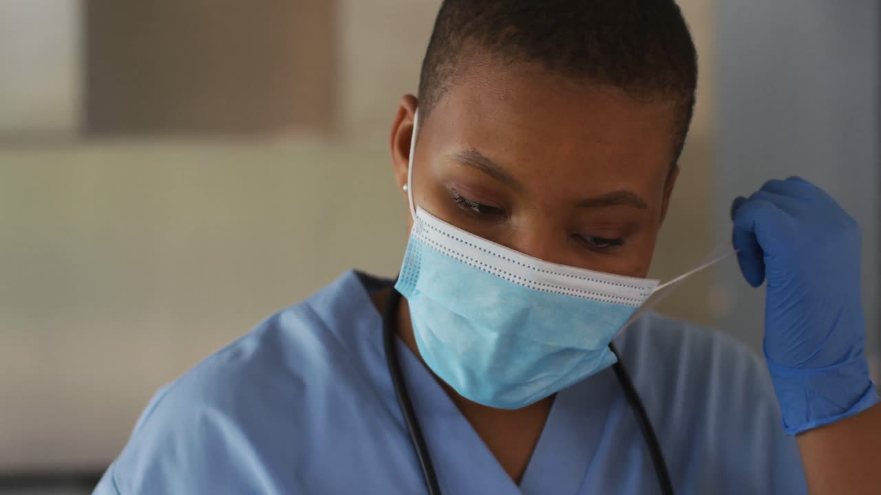 Dottoressa afroamericana che si toglie la mascherina e respira profondamente.