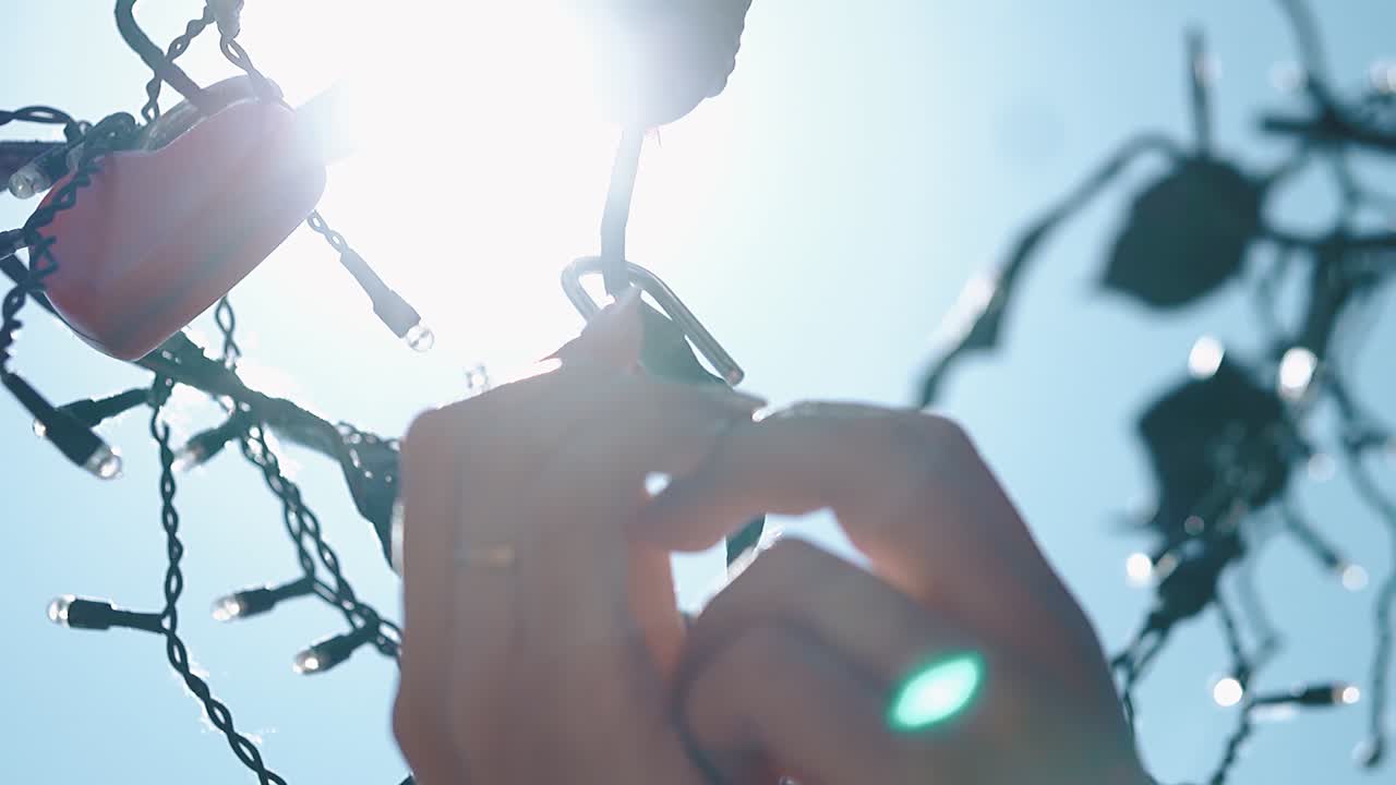 Newlyweds hang a lock on a love tree close-up slow motion