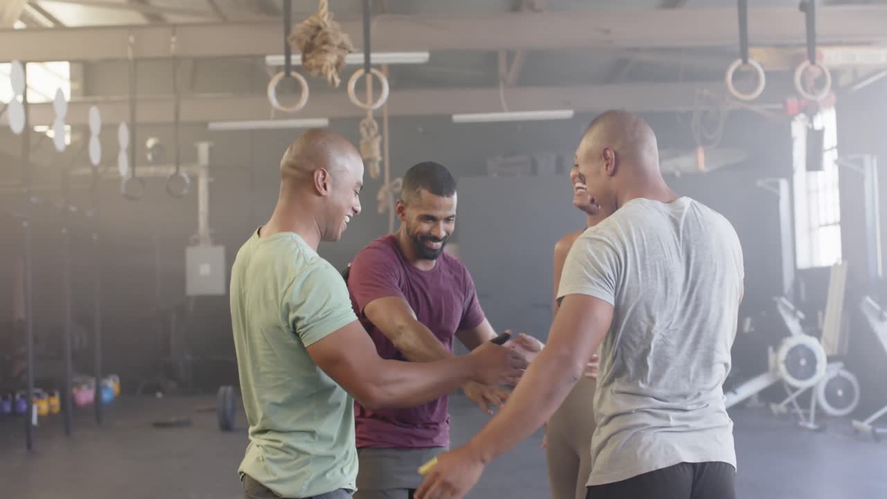 grupo diverso sonriendo y apilando las manos después del entrenamiento en clase de fitness en el gimnasio, en cámara lenta