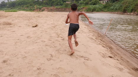 boy running on beach by river