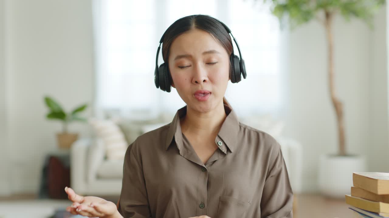 POV young Asian woman wearing headphone talking on video call conference or virtual meeting on laptop computer work from home