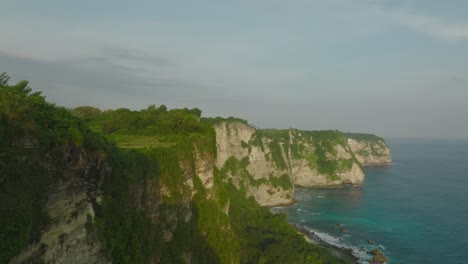 Tropical-limestone-cliffs-of-Nusa-Penida-with-blue-sea-water,-aerial