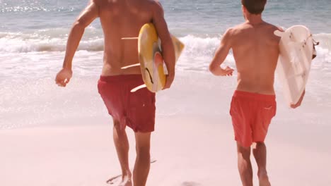 dos surfistas corriendo para entrar en el agua