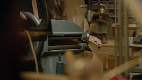 young female shoemaker cutting shoe leather on old fashioned workshop equipment close up slow motion