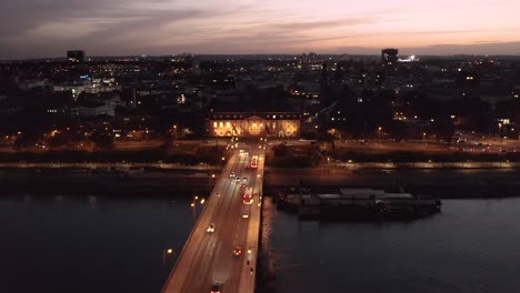 Mainz-Crossing-Bridge-Drohnenaufnahme,-Die-Menschen-Zeigt,-Die-Direkt-Nach-Sonnenuntergang-Mit-Dem-Auto-über-Die-Alte-Brücke-Nach-Hause-Kommen,-Wobei-Ein-Leuchten-Am-Himmel-Zurückbleibt