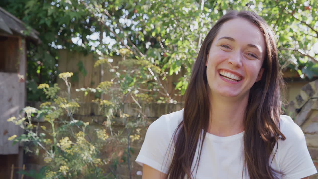 retrato de una mujer sonriente en casa en el jardín contra el sol abrasador