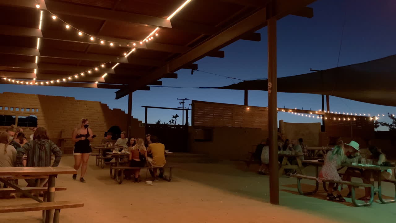 Timelapse at dusk of People eating at an outdoor resturant during covid, Slow right pan, California USA