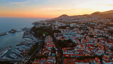 orange roofs of the multiple white houses located on the top of the mountain slope. sunset view of the town in the madeira islands, portugal. top perspective.