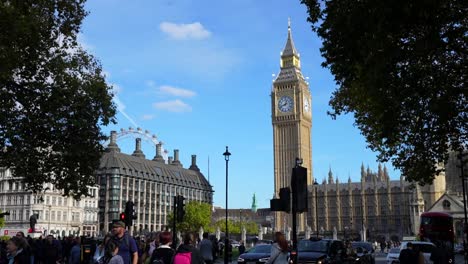 elizabeth tower and london eye with tourists and traffic under a bright sky in westminster, london