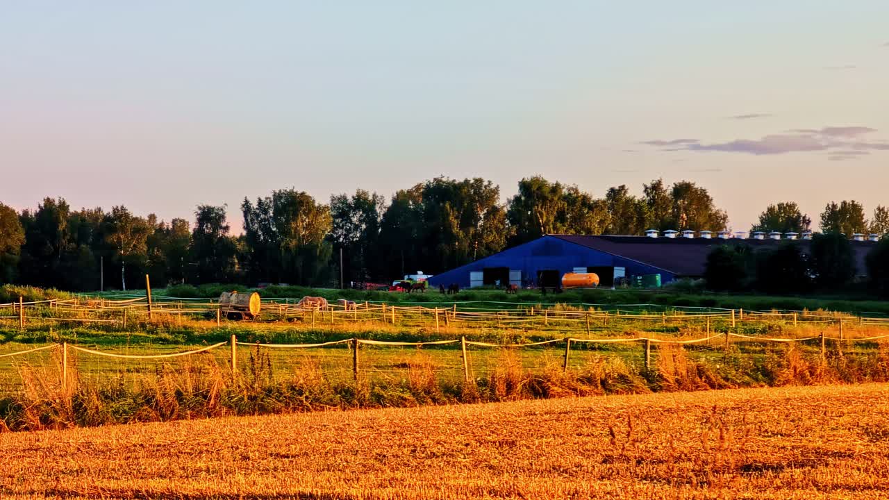 Ackerland mit goldenem Feld und Bauernhaus unter einem warmen Sonnenuntergangshimmel