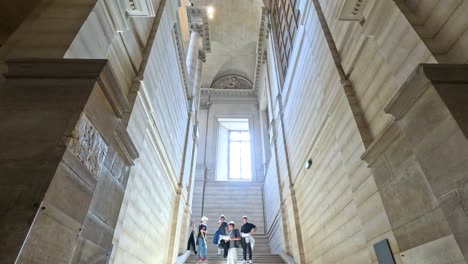 people climbing stairs inside the louvre museum