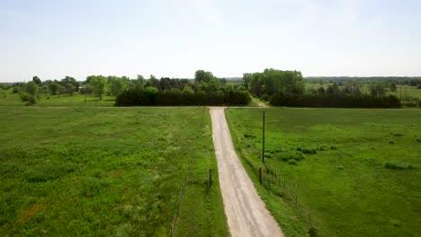 Aerial-horse-trailer-starts-its-ride-up-a-rural-dirt-road,-Kansas,-Missouri