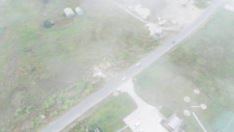 Top-view-through-the-fog-above-road-across-rural-areas-with-construction-sites-and-warehouses