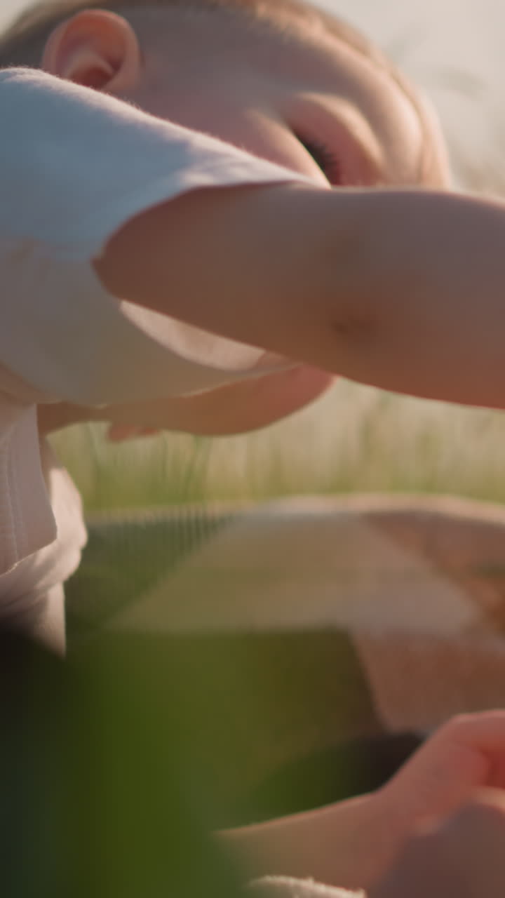 잔디에 앉아 을 나누고 있는 두 소년의 클로즈업  - 어린 소년은 친한 형에게  한 조각을 부드럽게 제공하여 형제 간의 유대와 보살의 순간을 포착합니다.